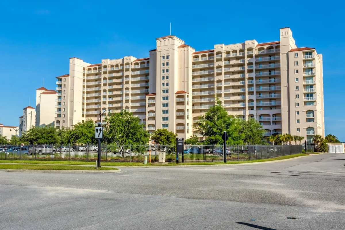 An inviting exterior shot of the large condominium building surrounded by manicured green landscaping and an entrance road. The atmosphere is warm and welcoming, hinting at the convenience and comfort of on-site amenities like parking and easy access to the resort’s attractions.
