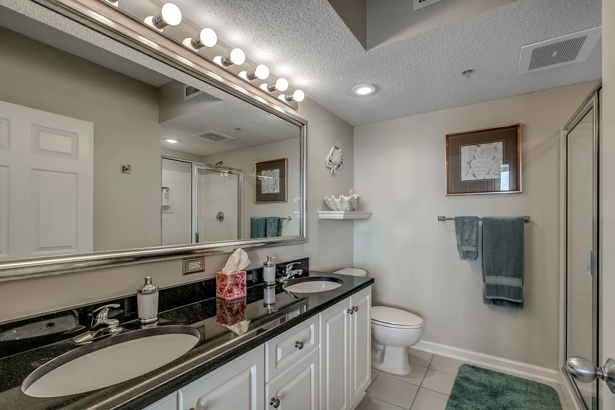 A modern bathroom with a spacious double sink vanity, large mirror, elegant lighting, and framed artwork above. The scene is inviting and tranquil, offering ample space for self-care routines and refreshing after a day of adventure.