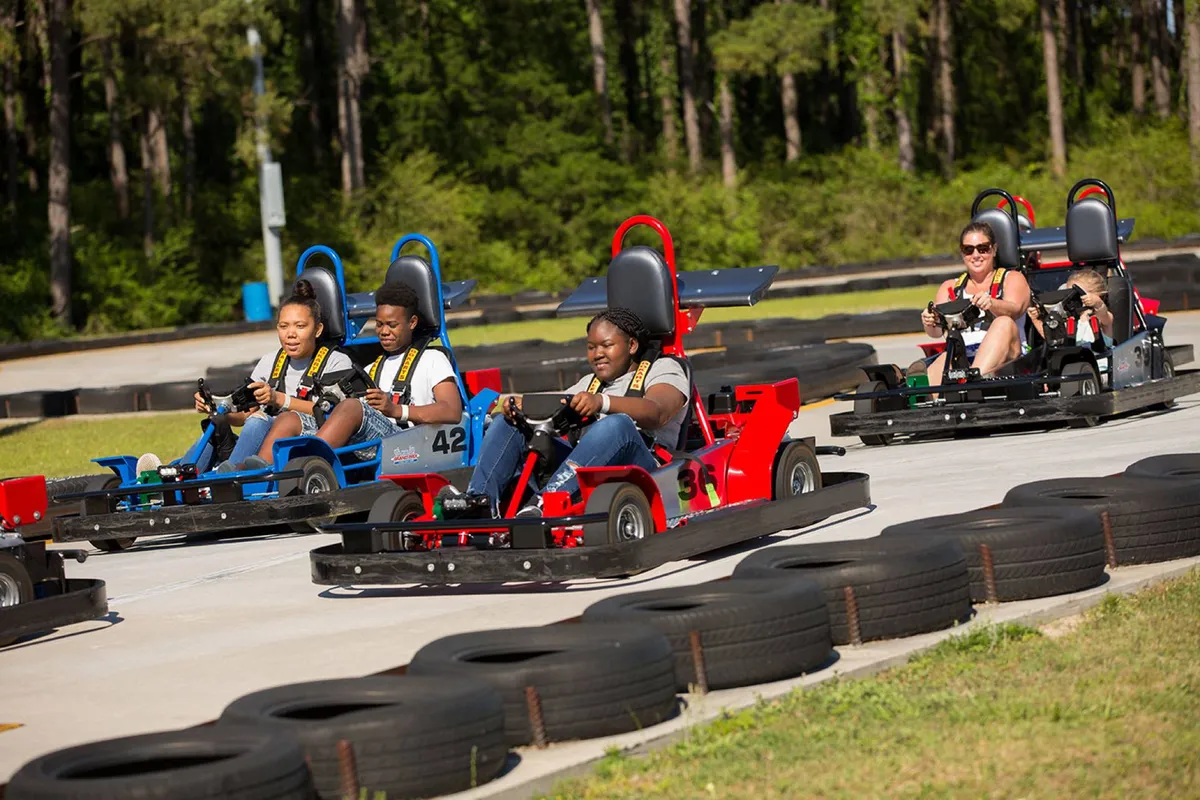 This image captures a lively go-kart track, with participants racing and smiling as they zip around the bends. The outdoor setting and energetic atmosphere are perfect for conveying family-friendly excitement and a sense of adventure.