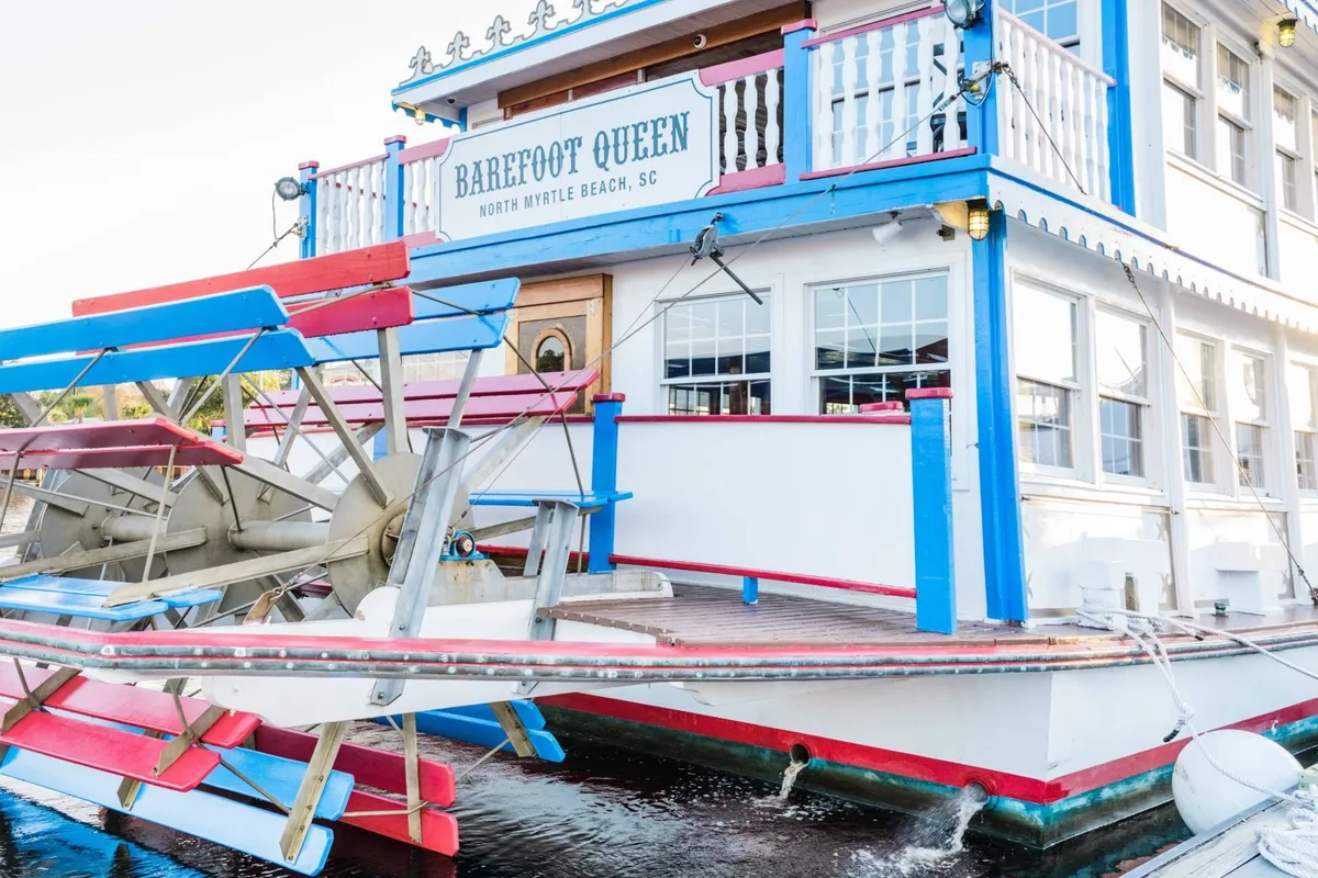 A vibrant exterior view of the Barefoot Queen paddleboat, with its colorful facade and classic paddle wheel. The image suggests the anticipation of a unique river cruise and the festive mood of a special outing.