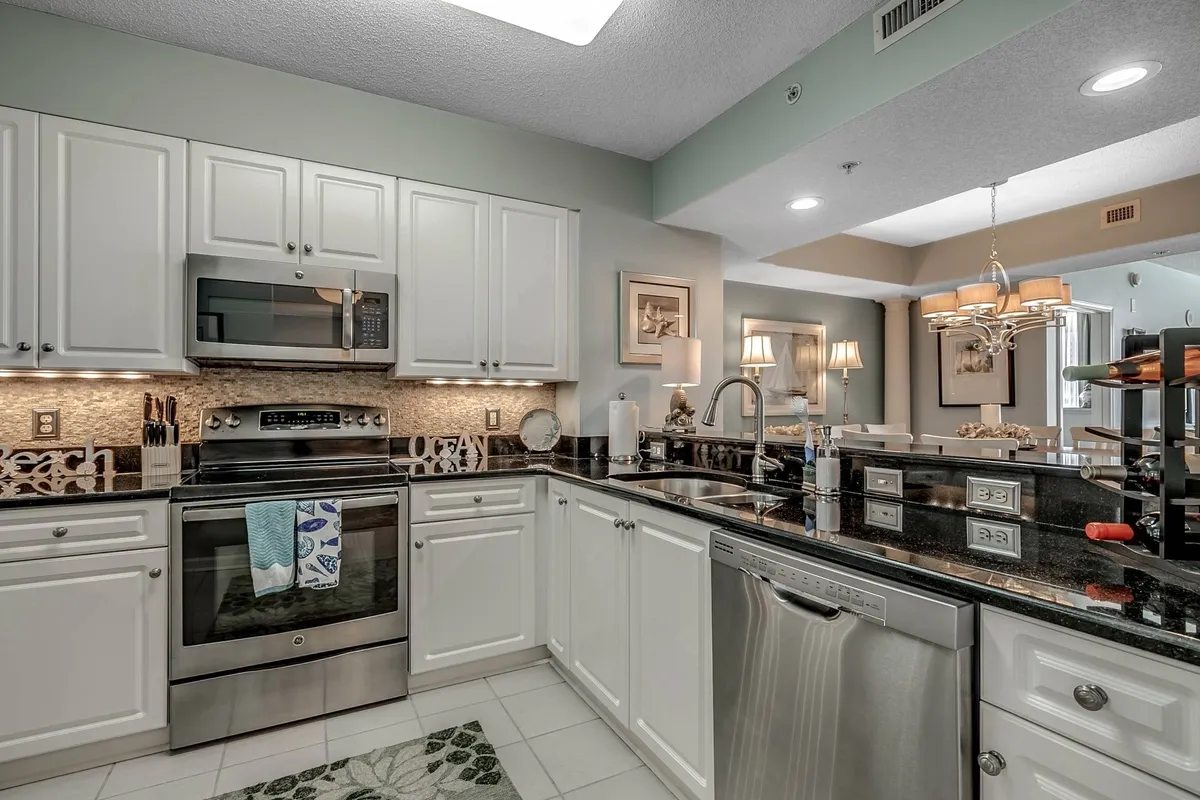 A modern kitchen featuring stainless steel appliances, granite countertops, a decorative backsplash, and a kitchen island. The space is bright and functional, inviting guests to cook, bake, or gather for casual conversation.