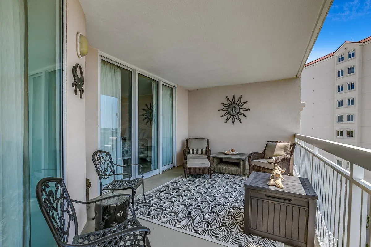 A close-up of the balcony’s seating area, featuring inviting wicker chairs, a decorative sun wall art, and an outdoor rug. The arrangement is oriented toward the view and exemplifies the comfort and functionality of the balcony, emphasizing it as an extension of the living space. The image suggests moments spent enjoying outdoor meals, reading, or simply relaxing while taking in the waterway's ever-changing light.